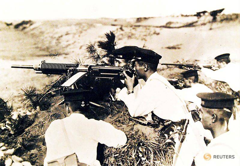 FILE PHOTO: Japanese soldiers wearing white uniforms and dress caps pose behind a heavy machine gun
